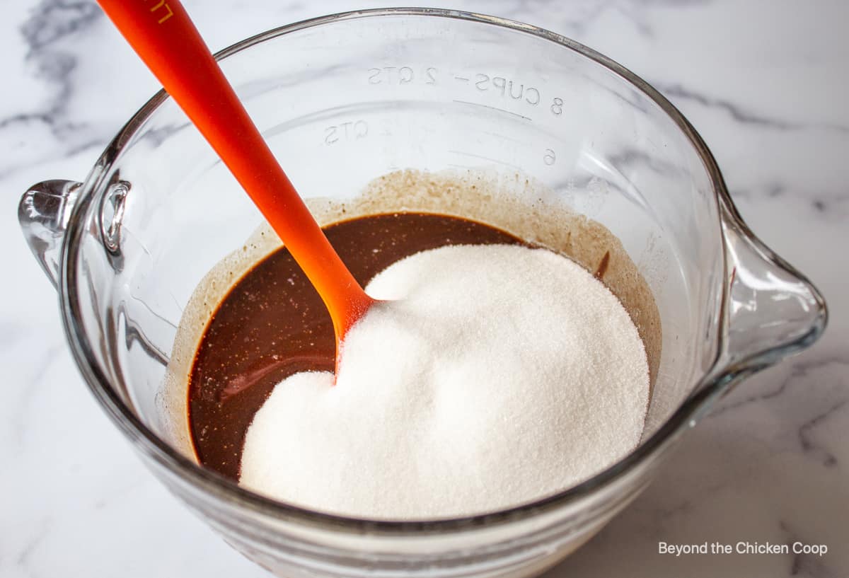 A glass bowl with melted chocolate and sugar.