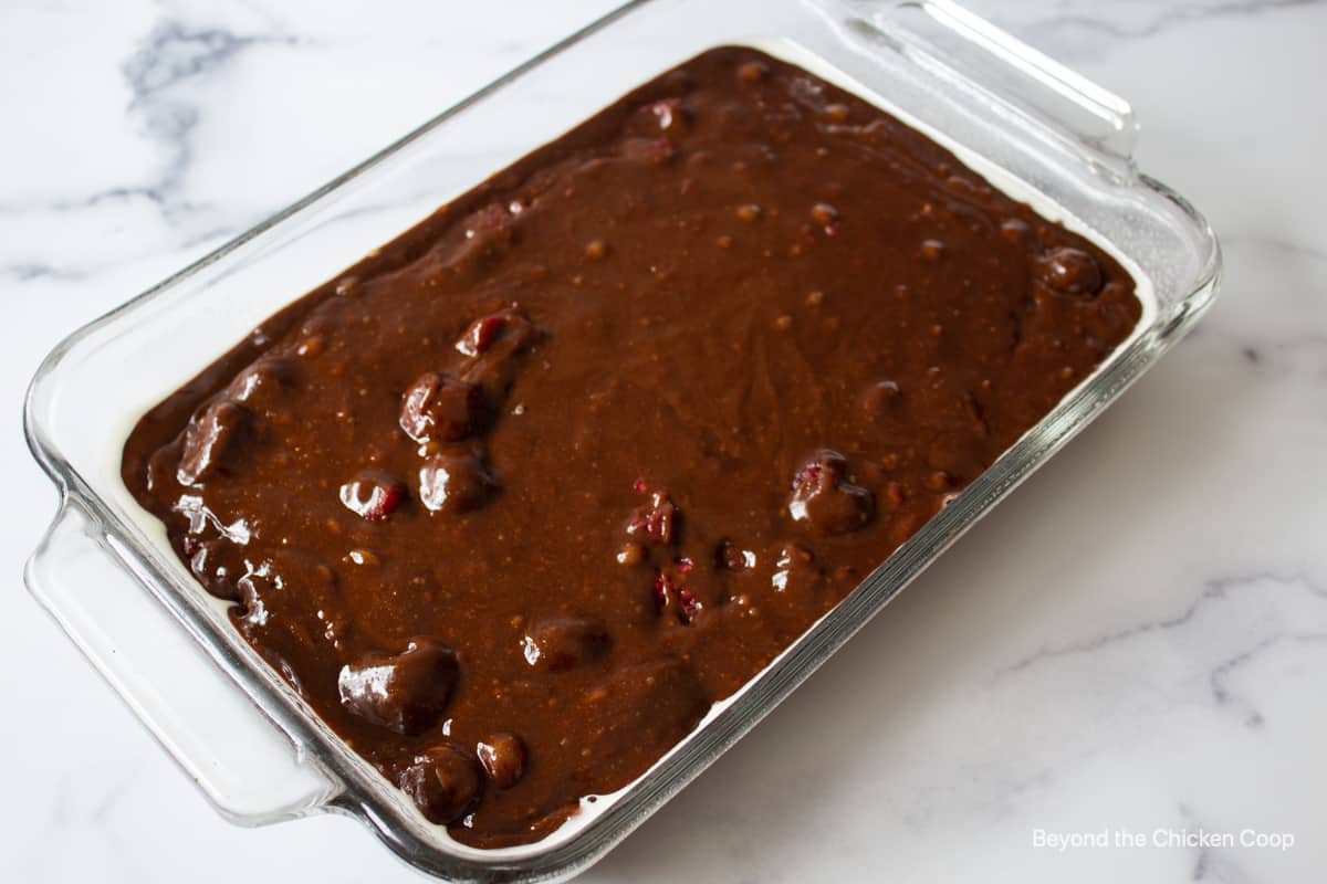 Brownie batter in a glass baking dish.