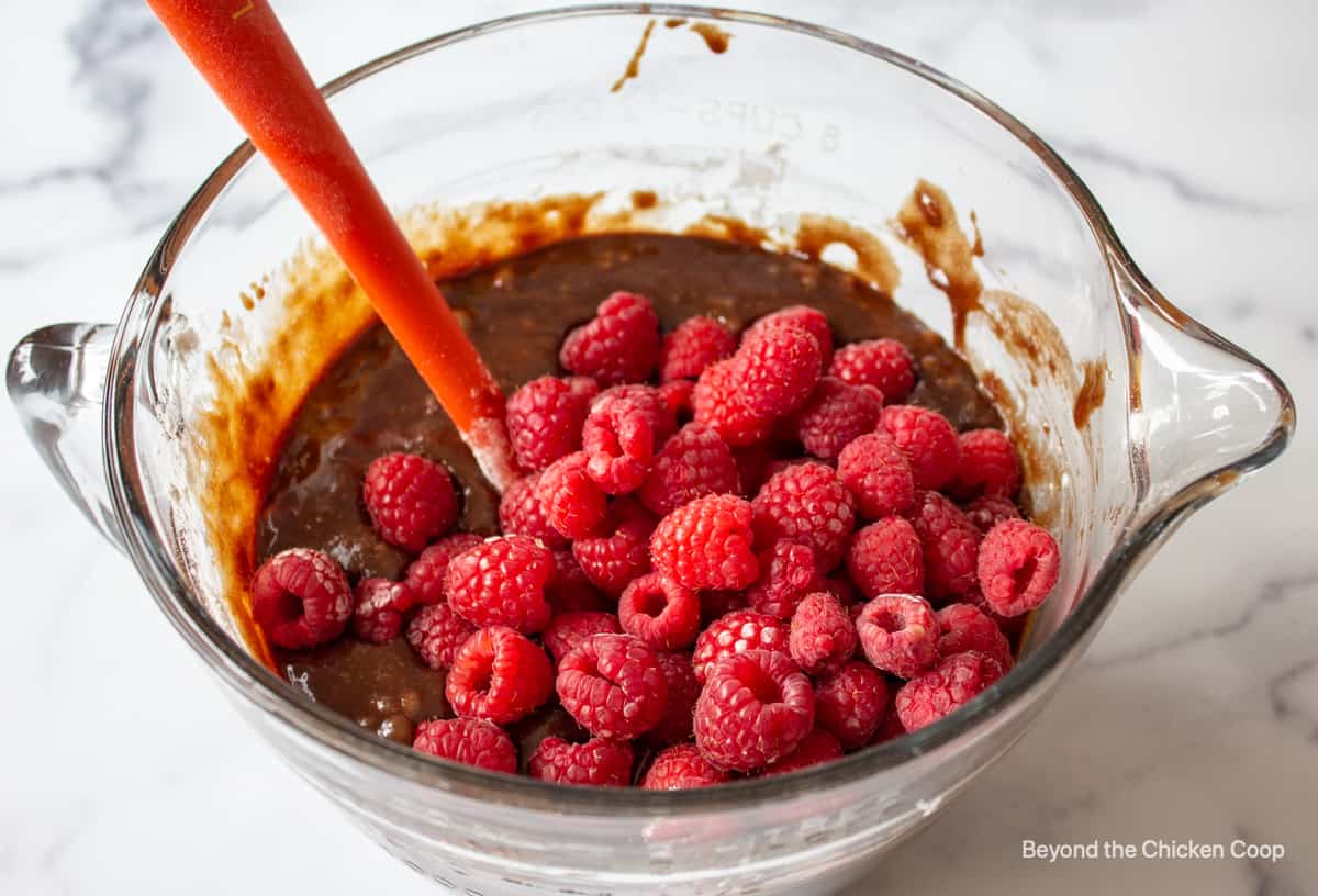Fresh raspberries in a bowl with brownie batter.
