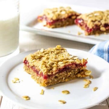 An oatmeal bar filled with raspberry jam on a white plate.