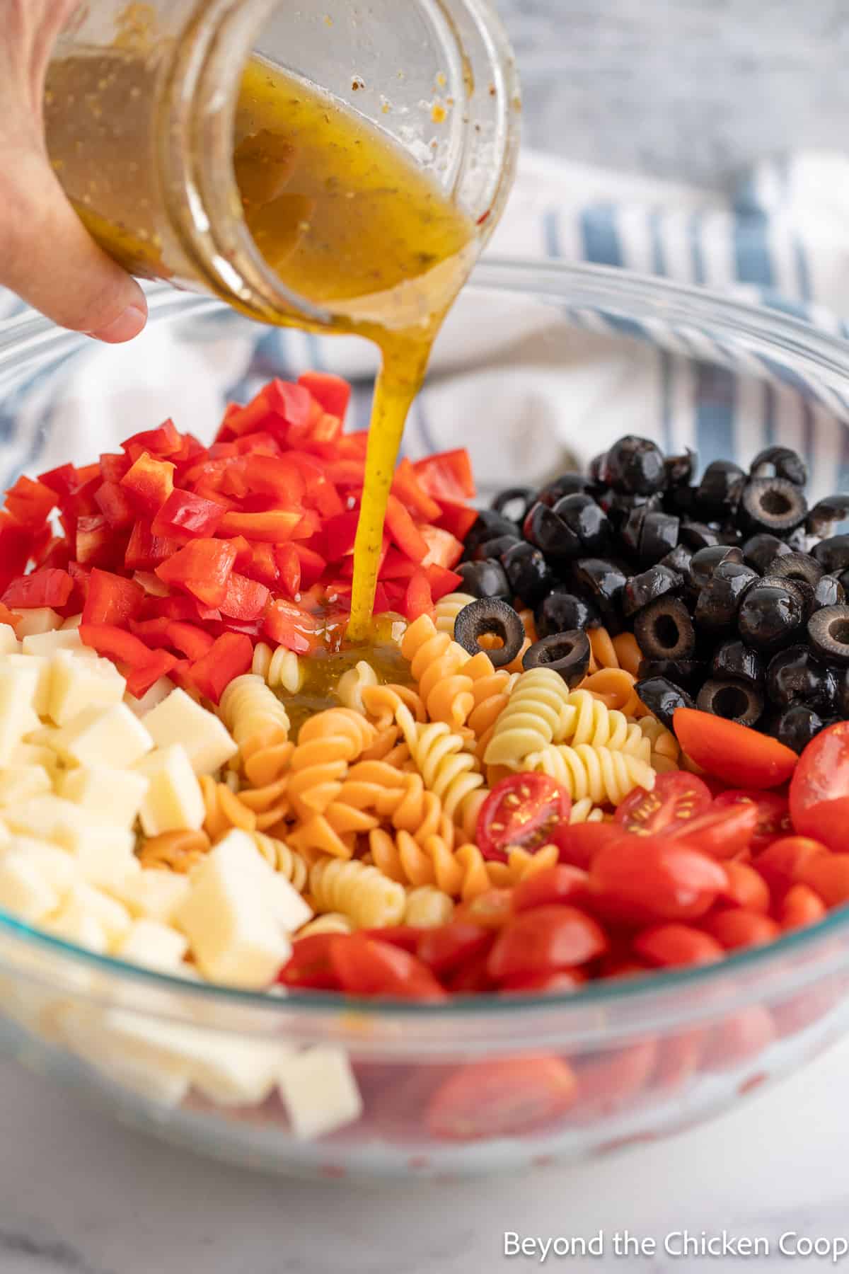 Pouring dressing over a pasta salad. 