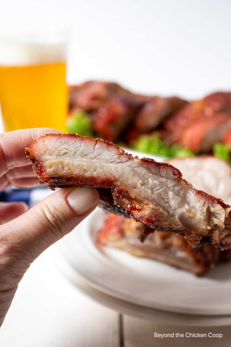 A pork rib being held in one hand.