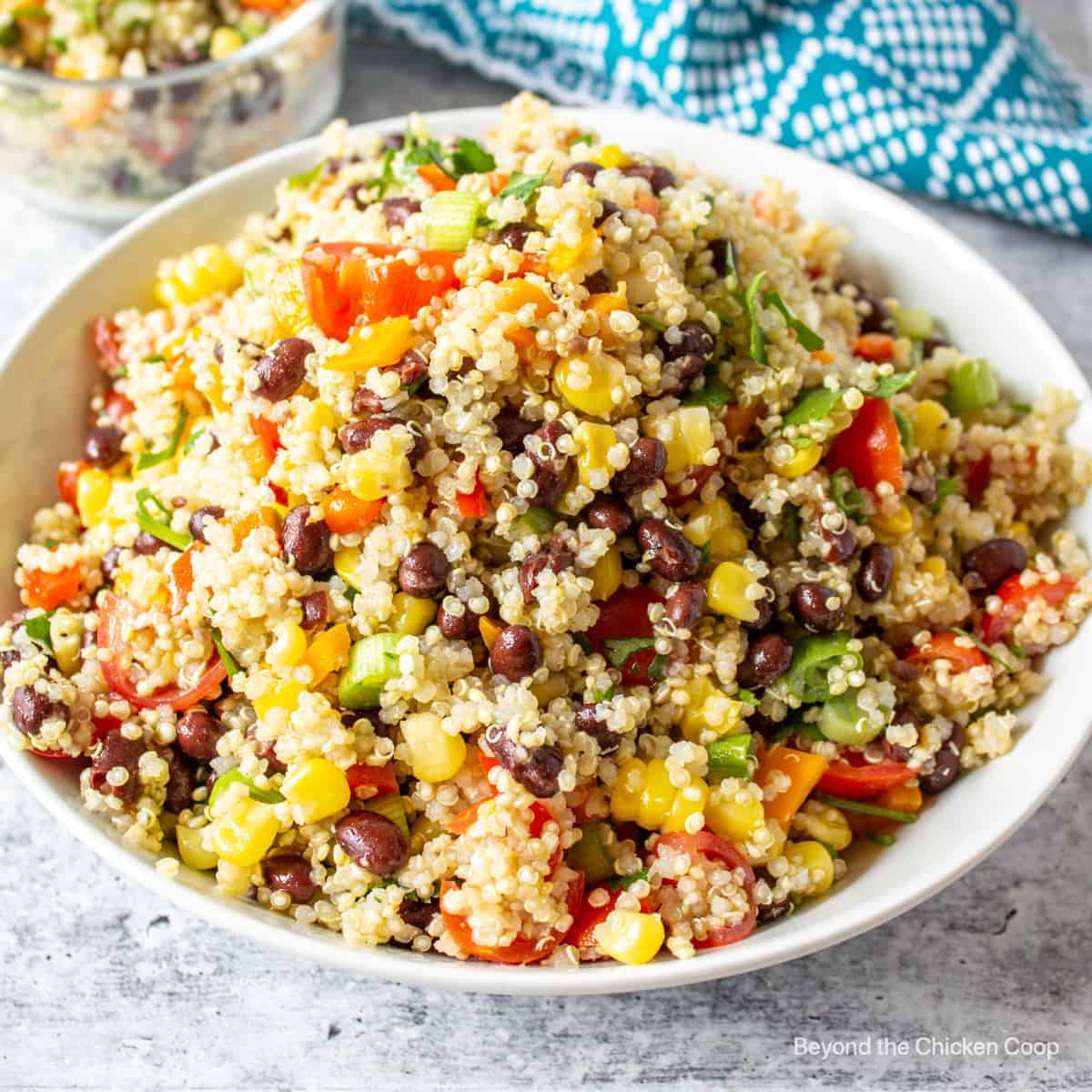 A large white bowl filled with quinoa, black beans, corn and chopped tomatoes.