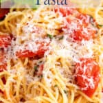Pasta with cherry tomatoes topped with cheese.
