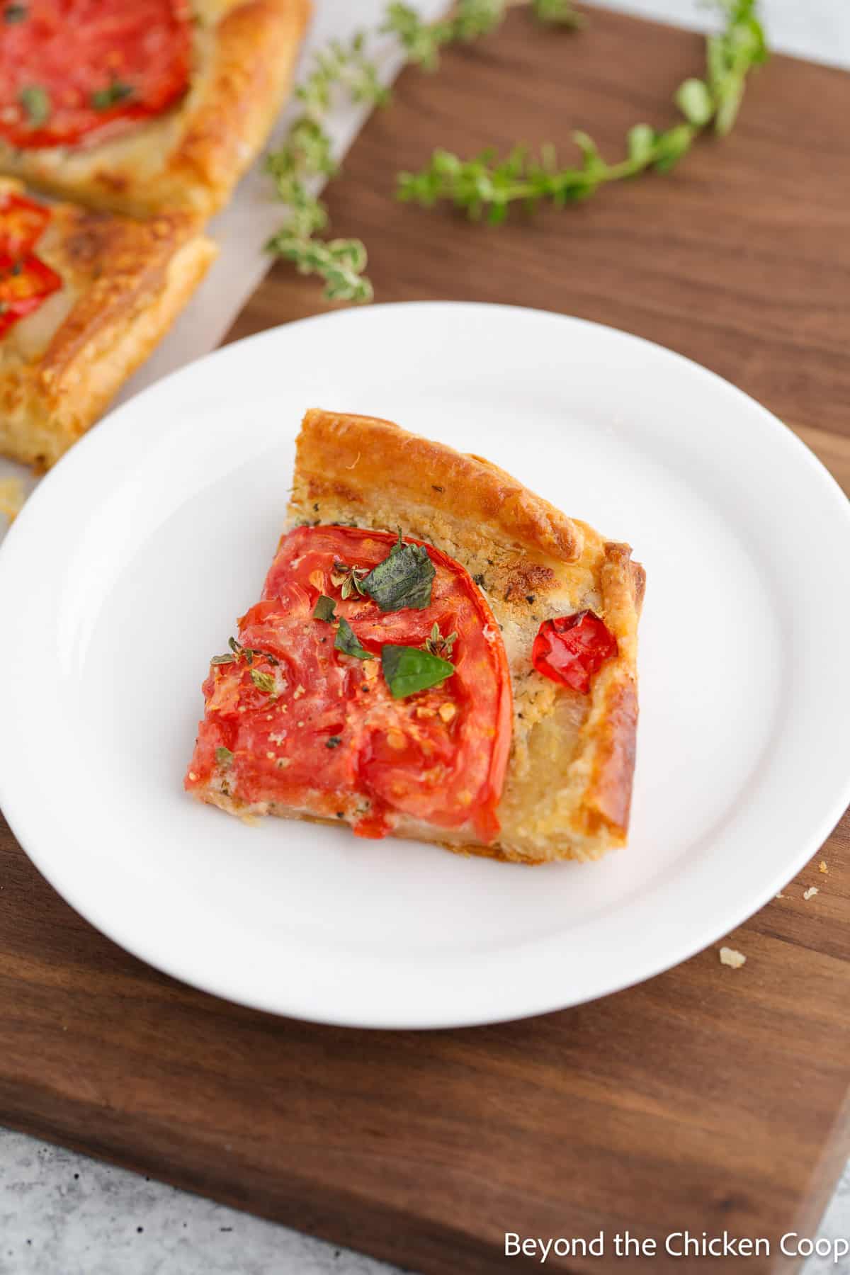 A slice of puff pastry tart topped with tomatoes. 