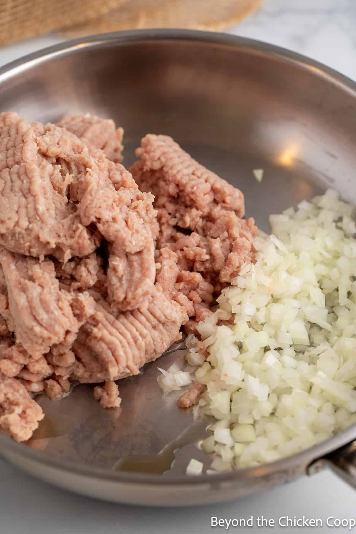 Ground turkey and chopped onions in a pan. 