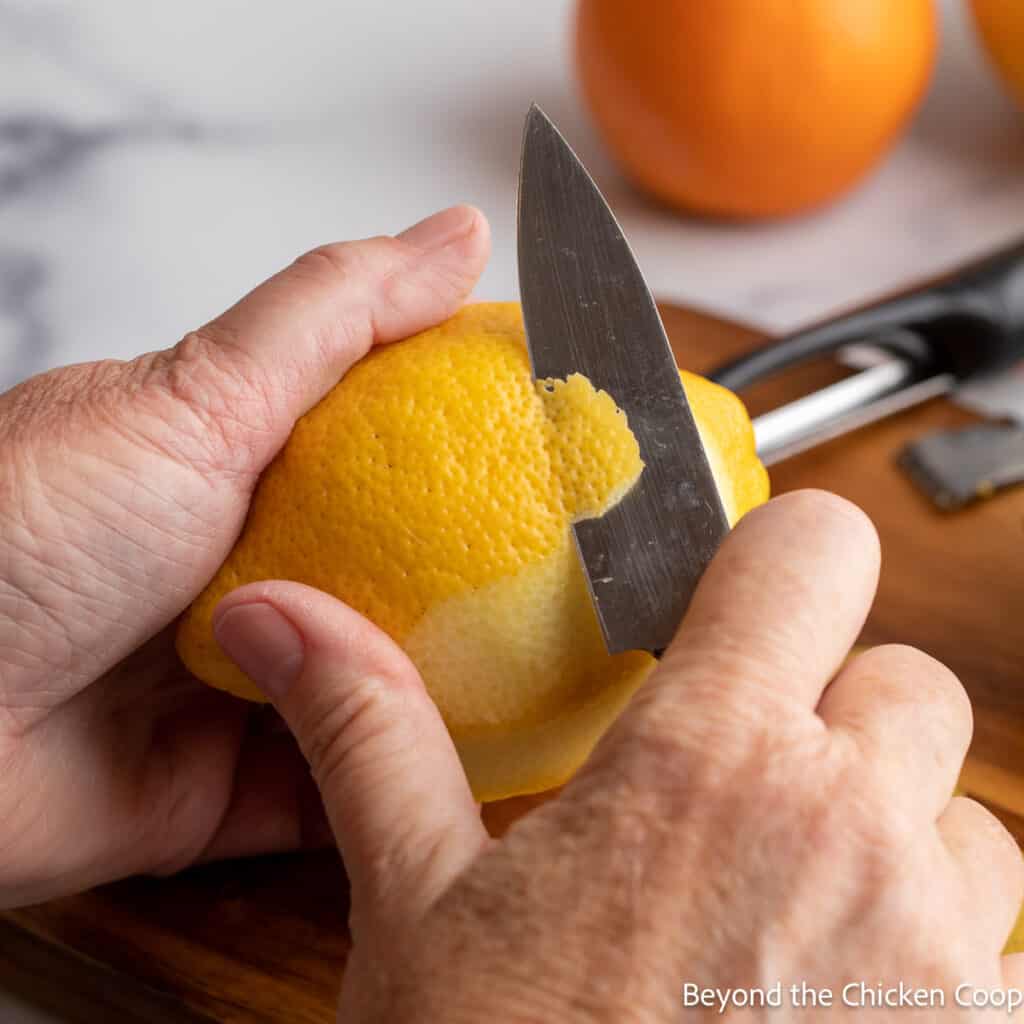 Removing the peel of a lemon with a small knife. 