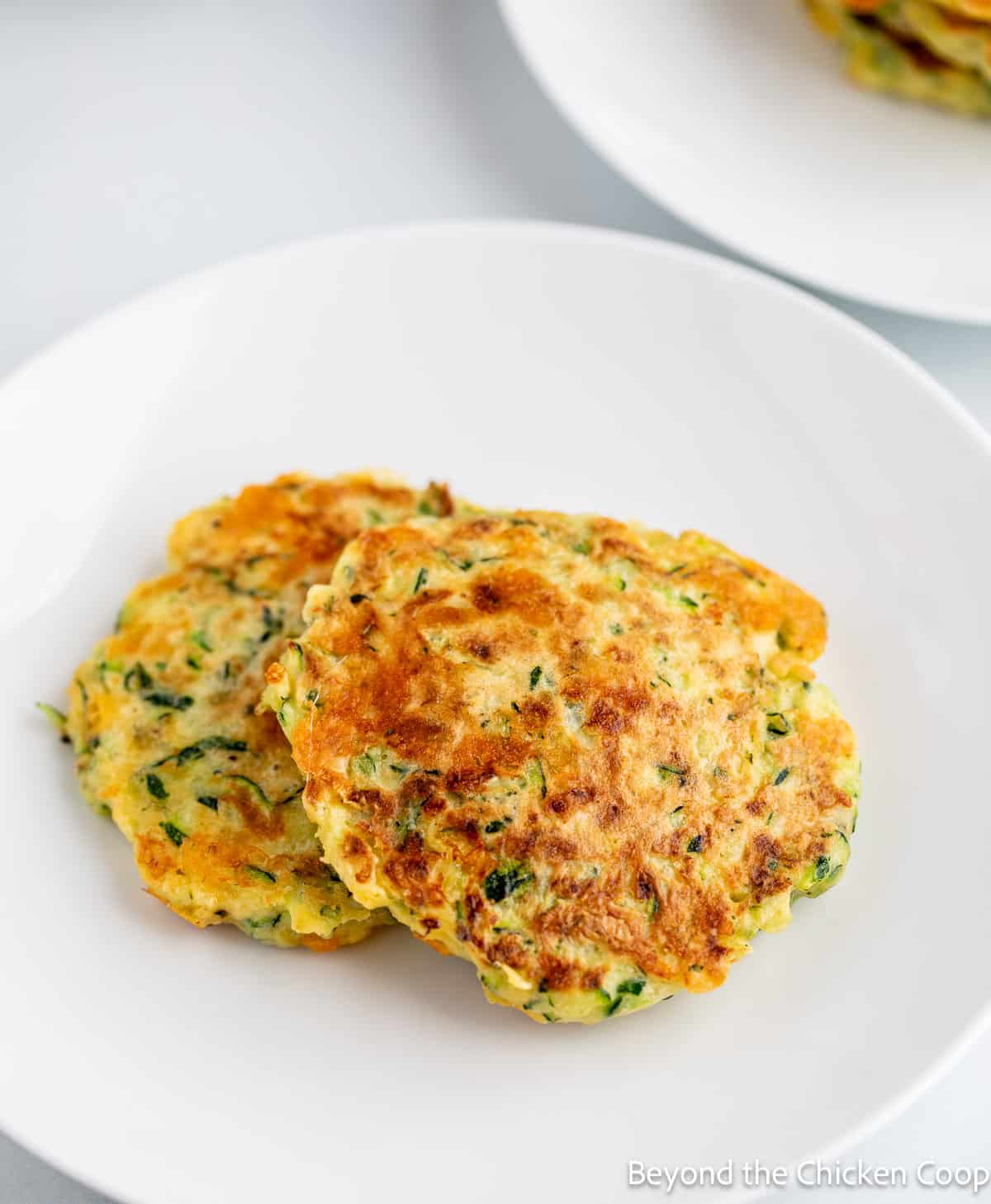 Two zucchini fritters on a plate. 