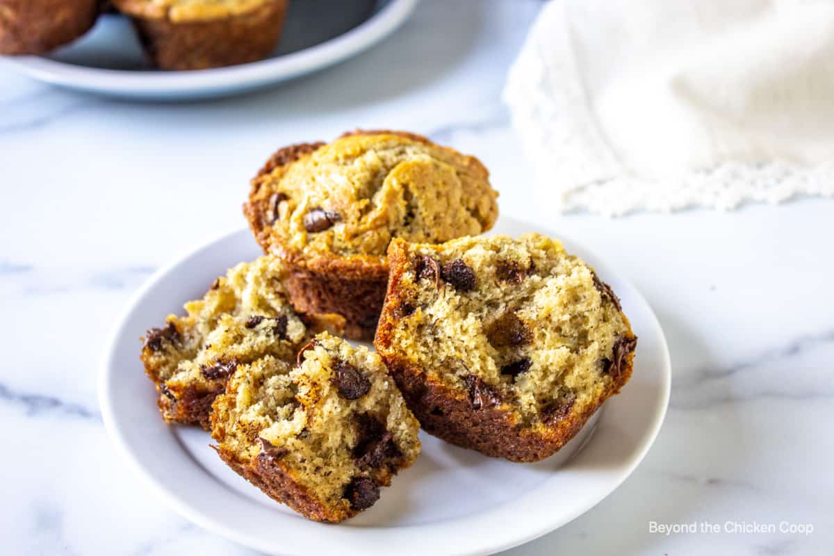 A muffin filled with chocolate chips split in half on a white plate.