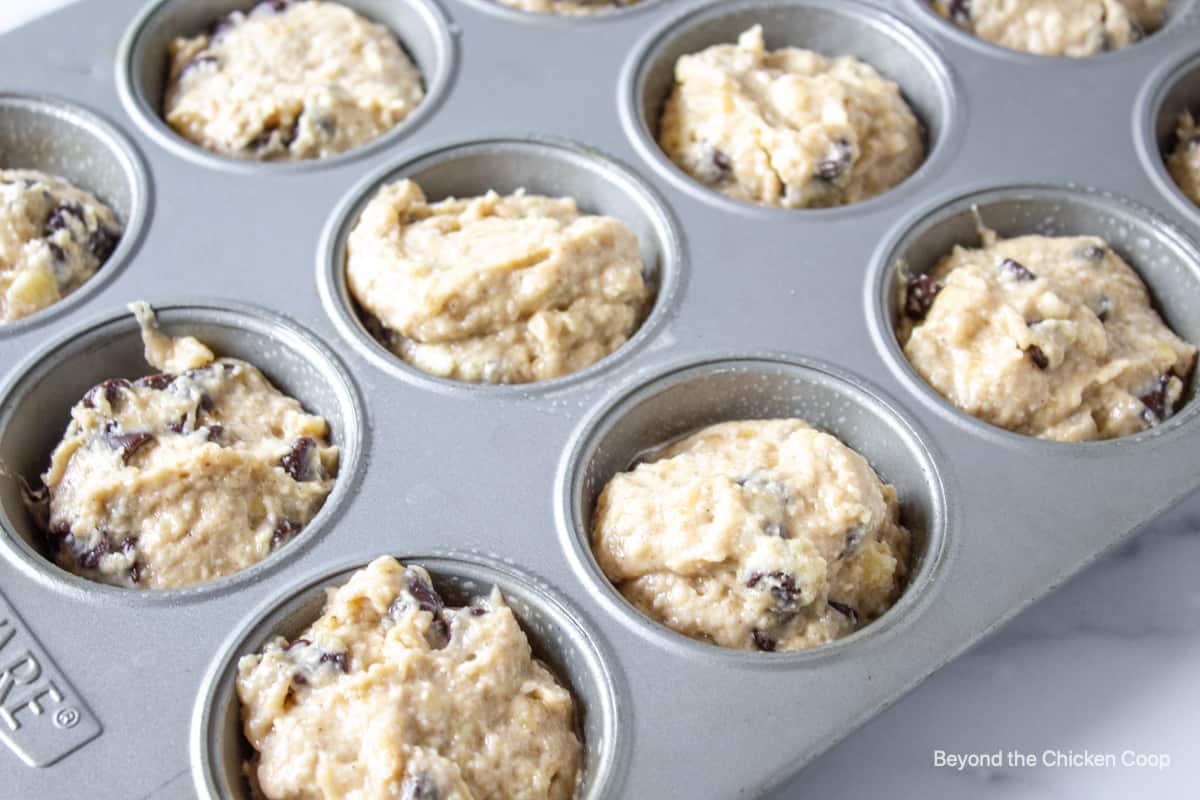 Muffin batter with chocolate chips in muffin tin.