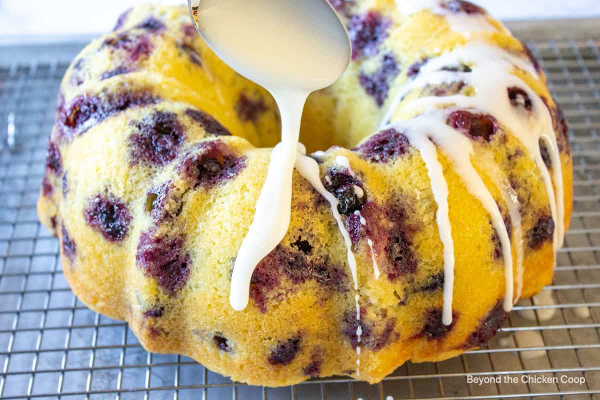 Icing being drizzled over the top of a bundt cake.