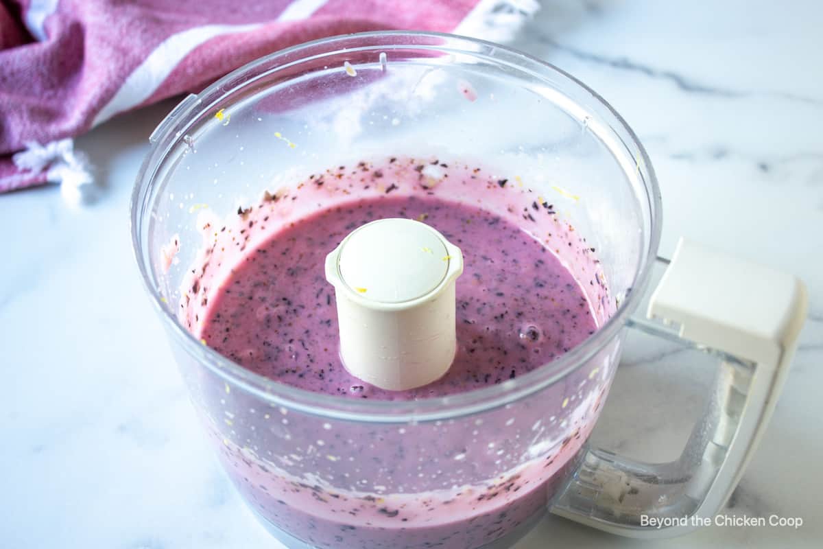 Pureed blueberries in a food processor bowl.