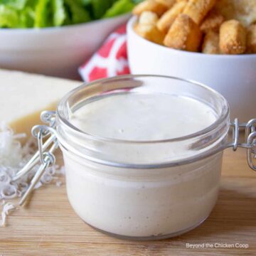 A glass crock filled with a creamy salad dressing.