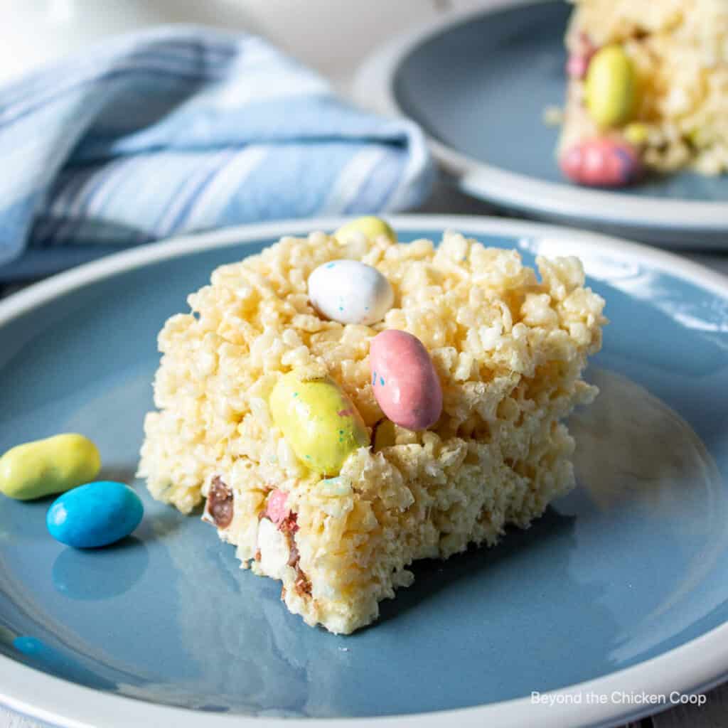 A rice krispie treat with malted candy eggs on a blue plate.