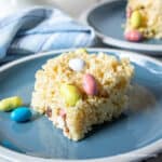 A rice krispie treat with malted candy eggs on a blue plate.