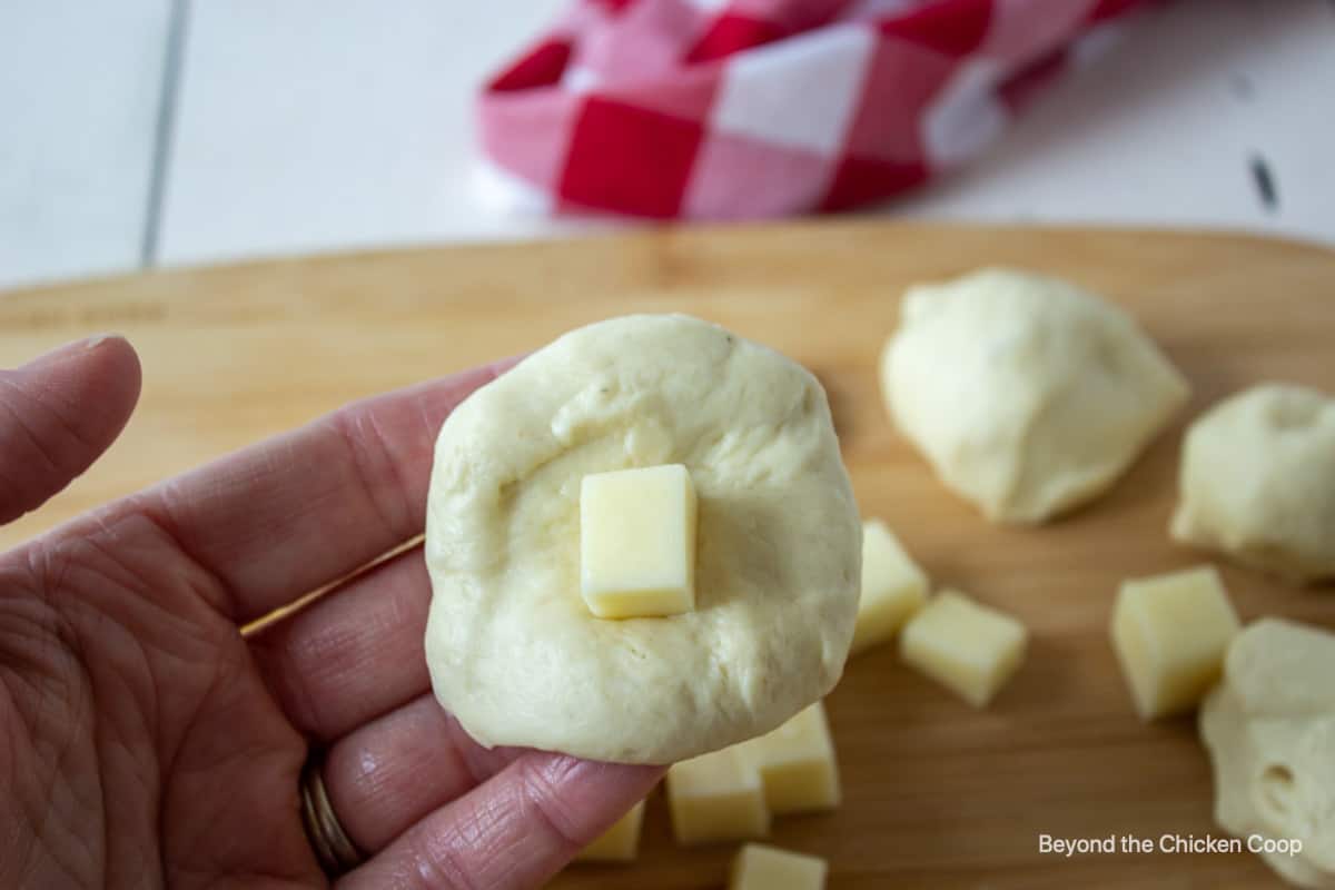 A flat piece of bread dough with a small cube of cheese in the center.