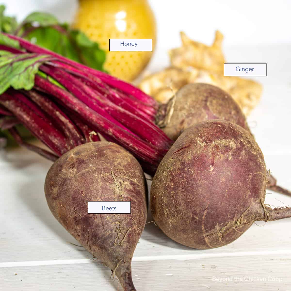 Beets, ginger and honey displayed on a white board.