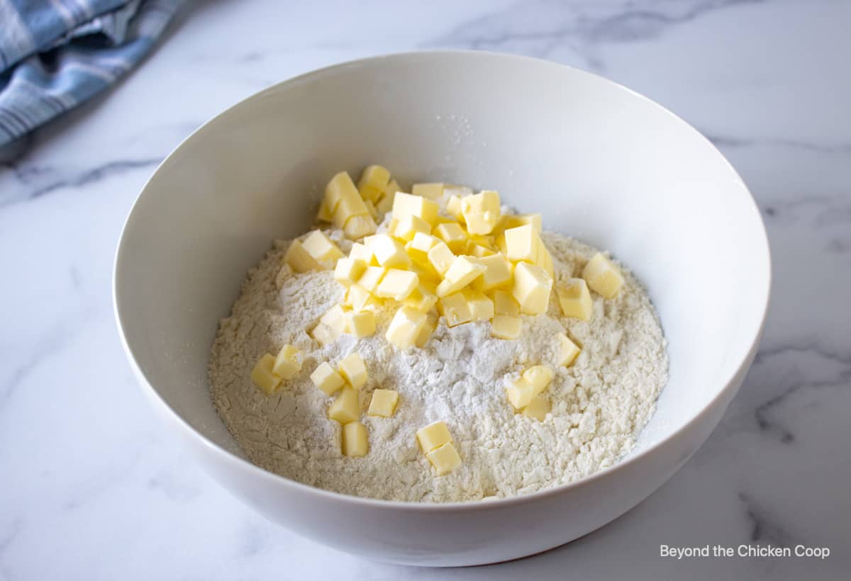 A white bowl with flour and small cubes of butter.