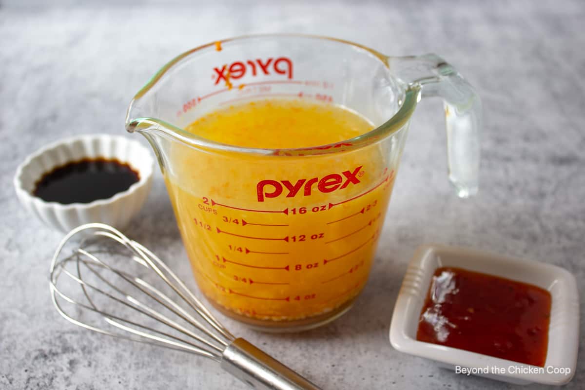A glass measuring cup filled with an orange mixture.