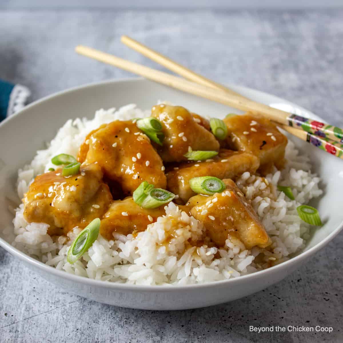 Orange Chicken A white bowl filled with orange chicken with rice.