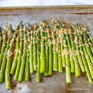A baking sheet filled with asparagus topped with parmesan cheese.