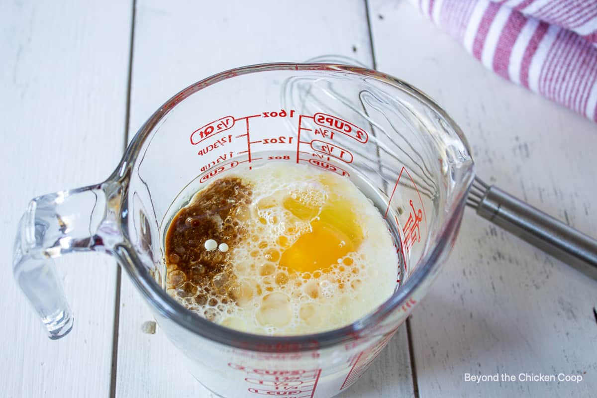 A glass measuring cup with egg, milk and vanilla.