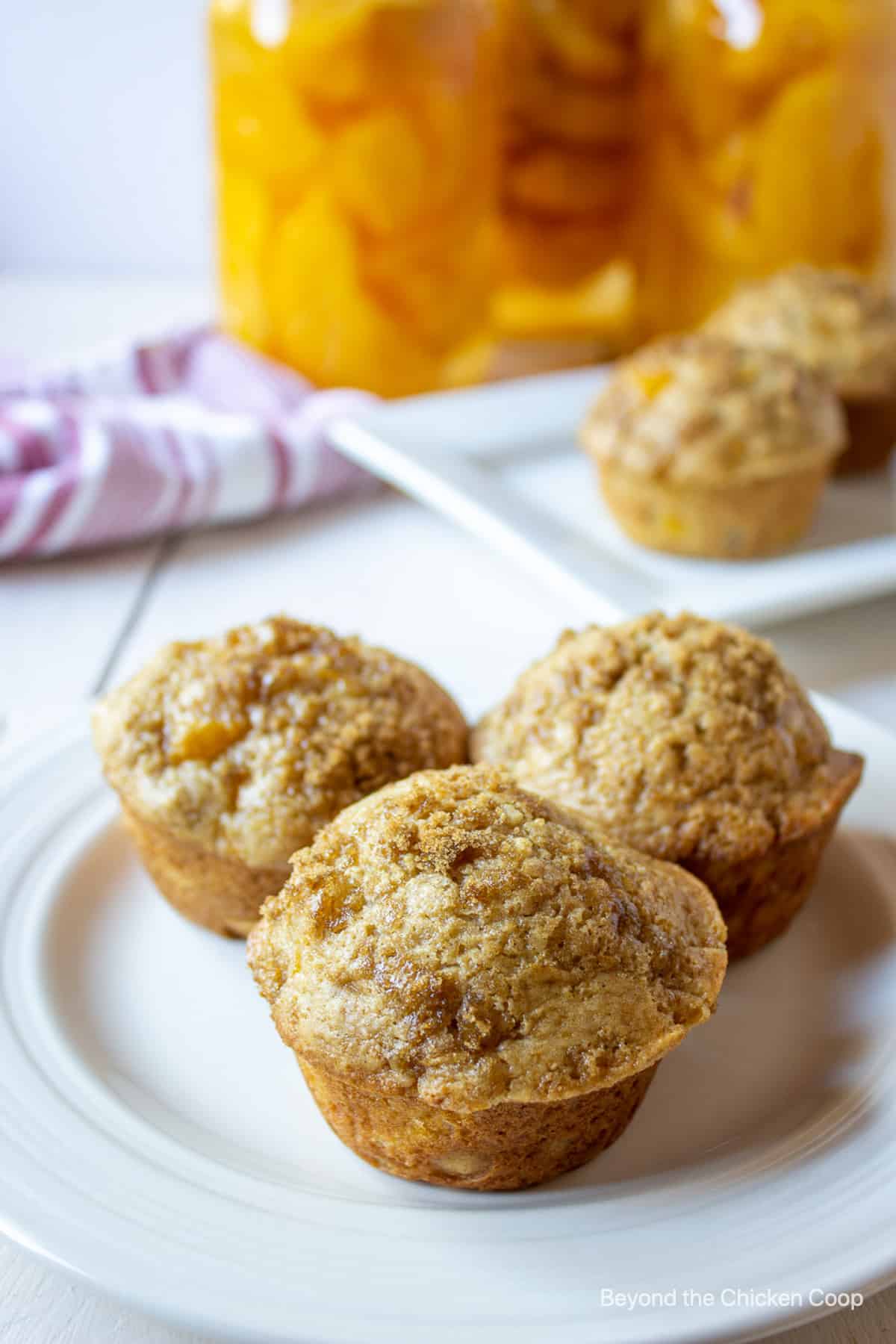 Three muffins with a crumble topping on a white plate.