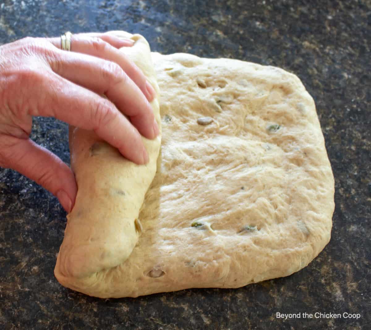 Rolling up bread dough into a log shape.