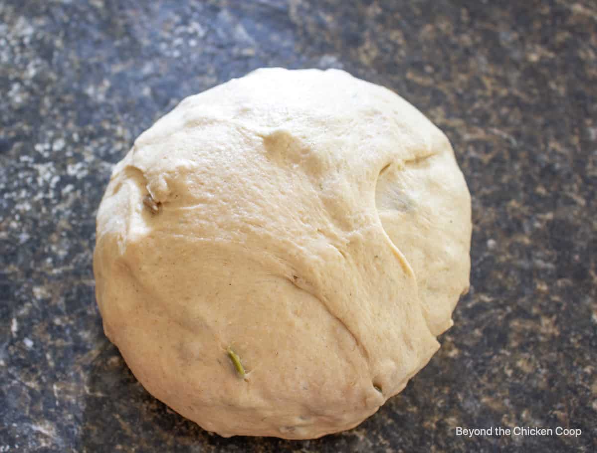 A round ball of bread dough on a counter top.