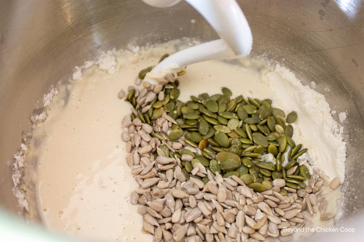 Pumpkin seeds and sunflower seed added to a mixing bowl.