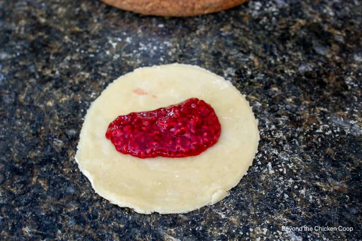 Raspberry filling in the center of a round piece of pie dough.