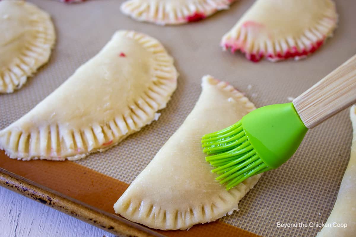 Brushing unbaked turnovers with an egg wash.