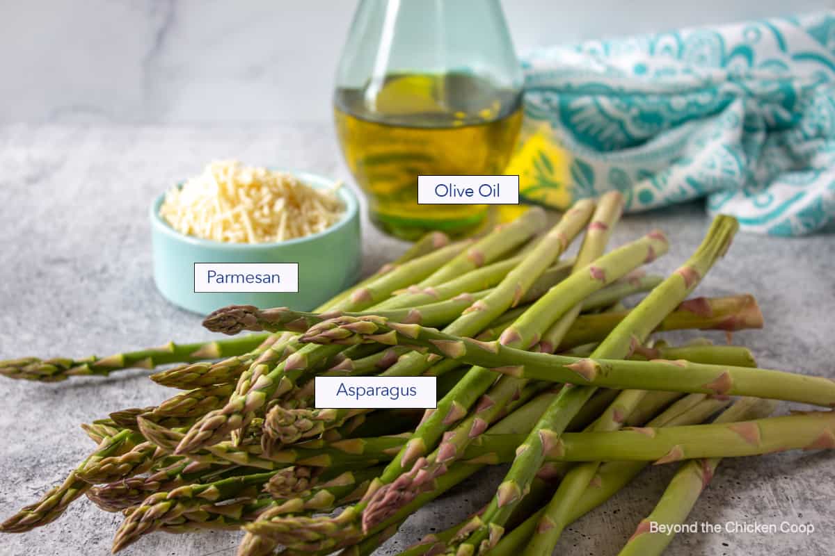 Fresh asparagus on a board with olive oil and parmesan cheese.