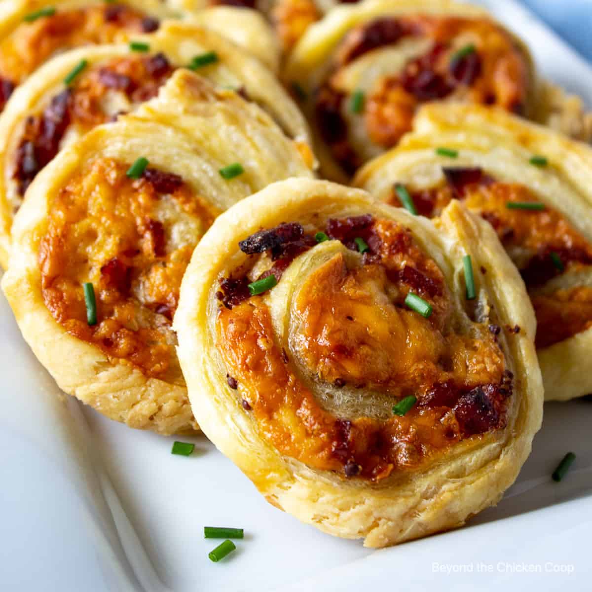 Puff pastry pinwheels with melted cheese on a plate.