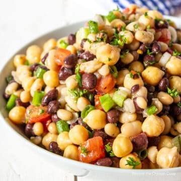 A white bowl filled with a bean salad with tomatoes.