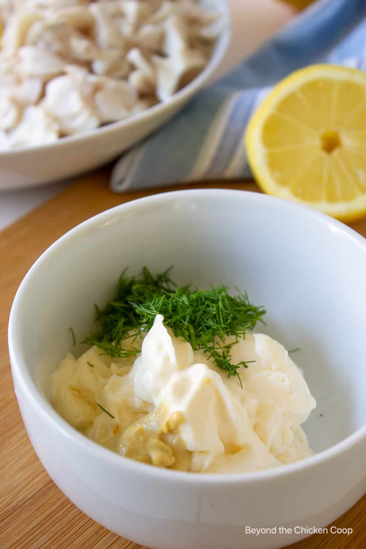 Mayonnaise and fresh dill in a white bowl.