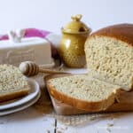 A loaf of wheat bread sliced on a wooden cutting board.