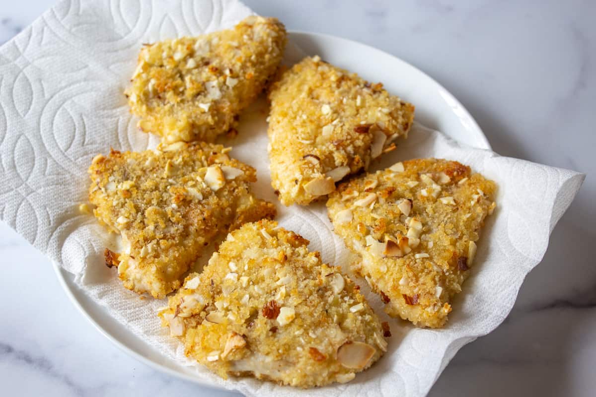 Cooked fish on a plate lined with a paper towel.