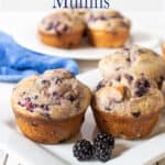 Muffins on a white tray with a few blackberries near the muffins.