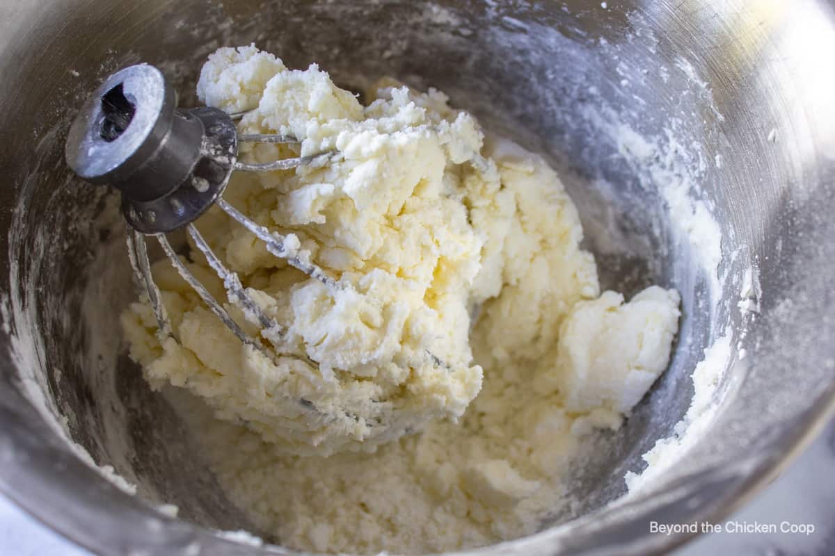 A very thick frosting on a large whisk in a bowl.