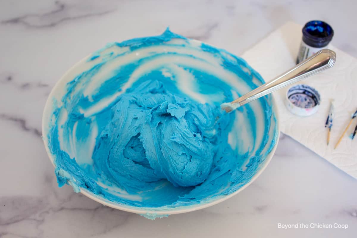 Blue frosting in a white bowl.