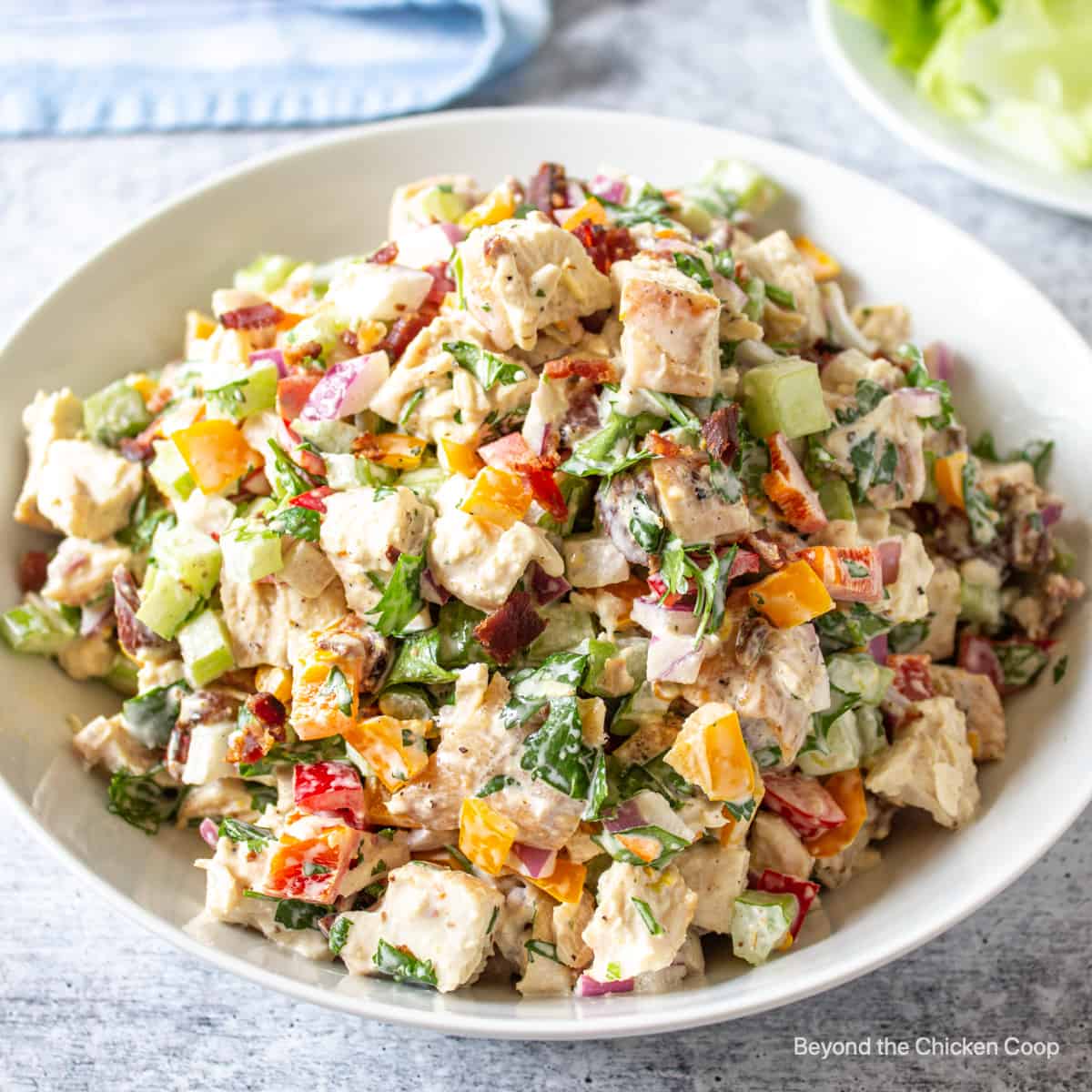 A white dish filled with a colorful chicken bacon salad.