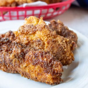 A white plate with three chicken strips.
