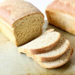 A loaf of home baked bread with three slices cut off the loaf.