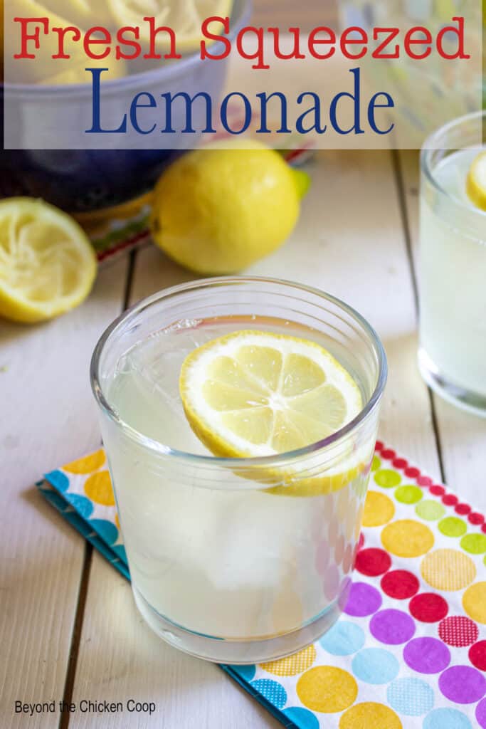 A glass filled with lemonade with a slice of a lemon floating on the top.