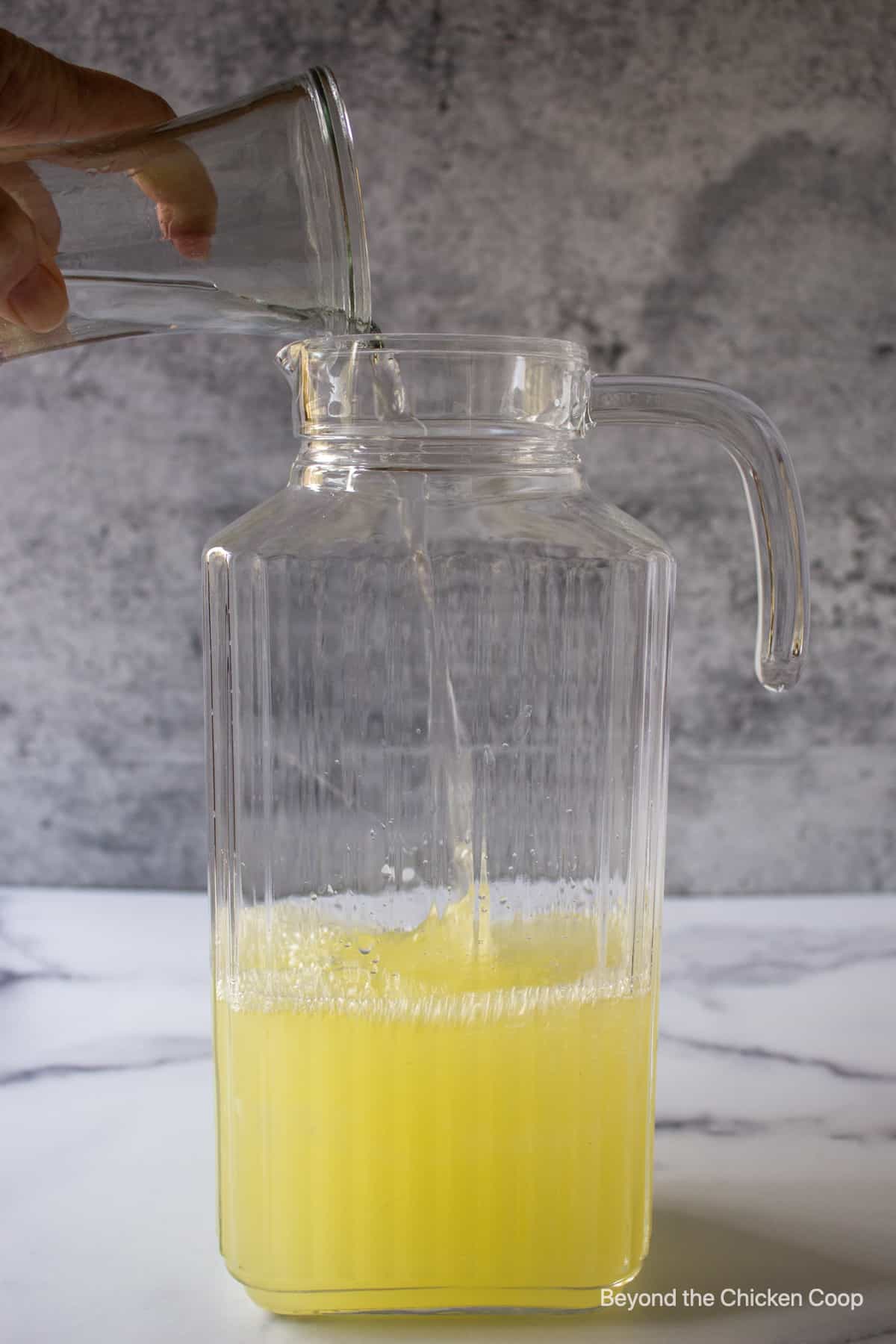 A glass pitcher filled with lemon juice. 
