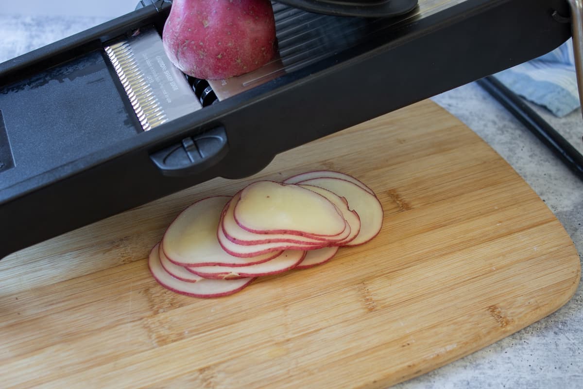 Red potatoes sliced on a mandoline.