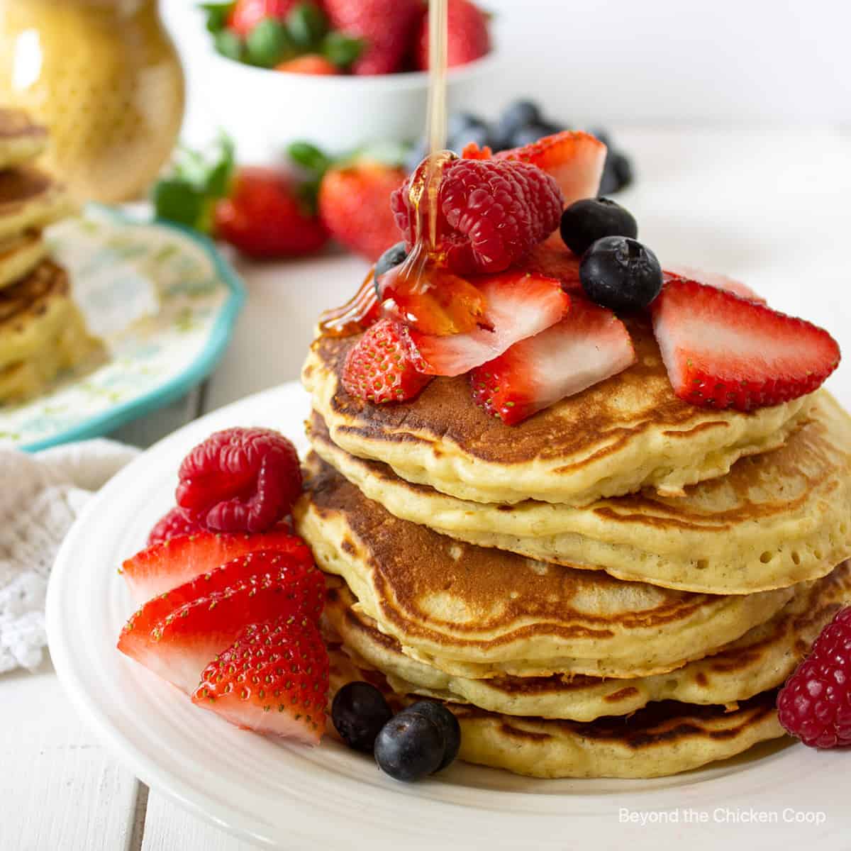 A stack of pancakes topped with fresh berries and a drizzle of syrup.