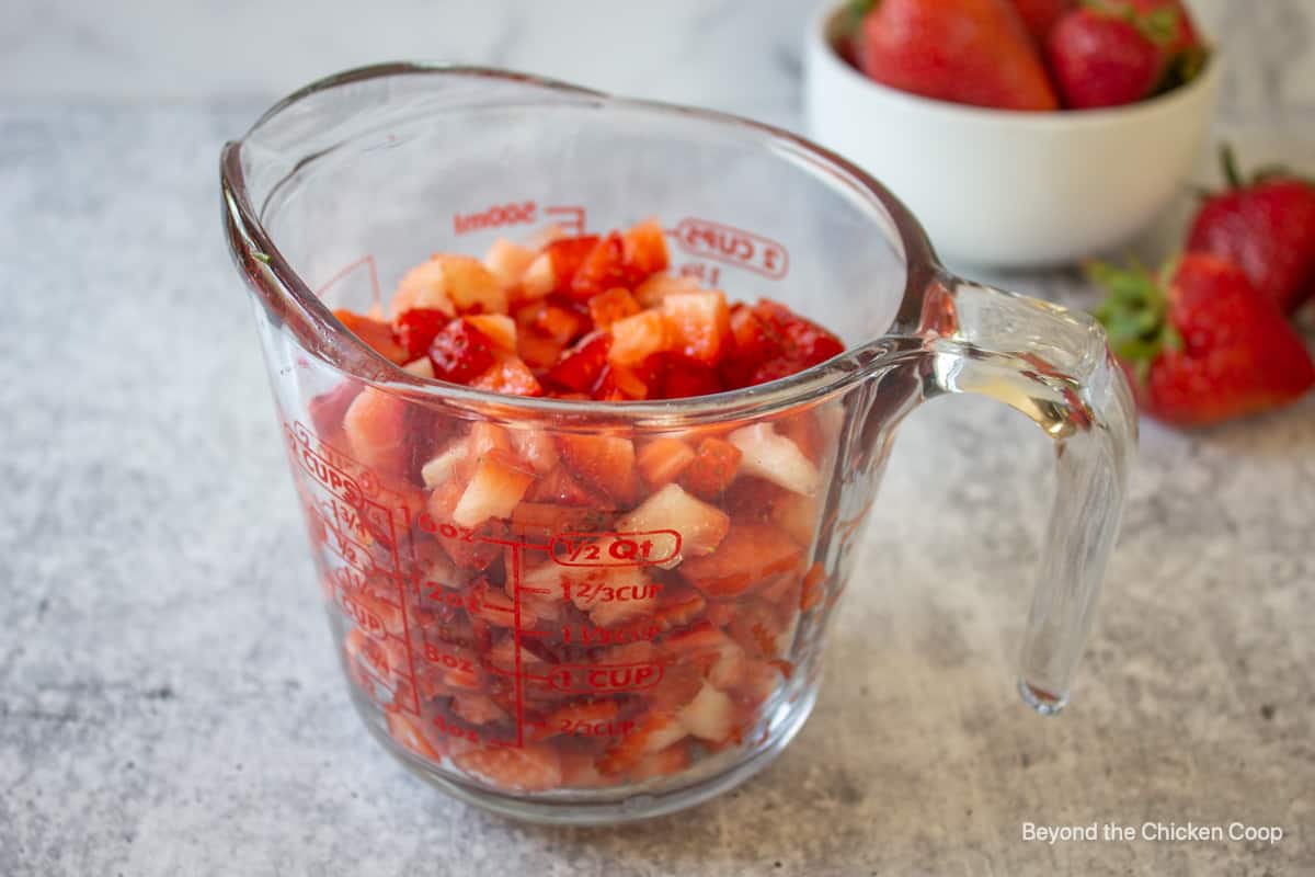 Diced strawberries in a glass measuring cup.