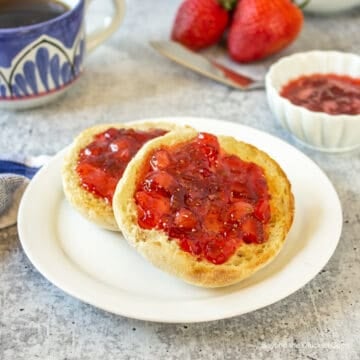 An english muffin topped with chunky strawberry jam.